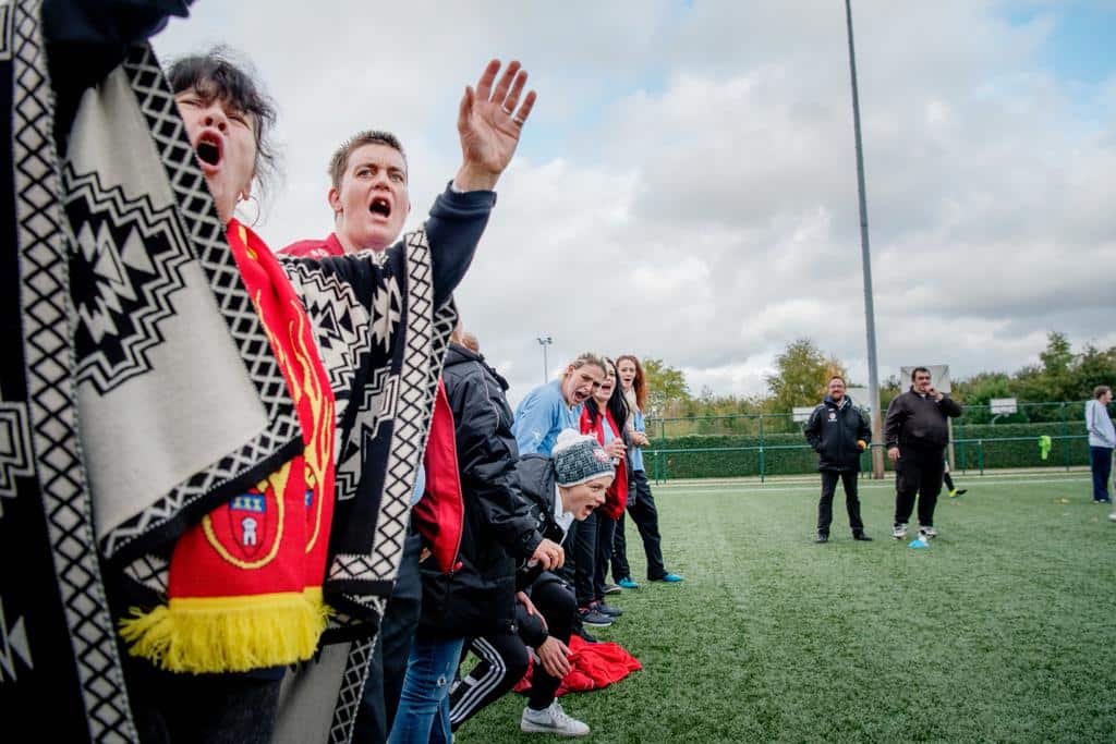 Supporters van Tounited Belgium bij een voetbalveld.