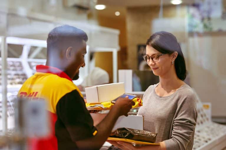 Male DHL employee scanning packages of female customer.